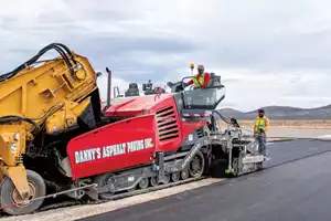 A crew lays asphalt for a new taxiway at an airfield in West Texas with a VÖGELE SUPER 2000-3i paver before smoothing it with a HAMM HD 13i tandem roller. 